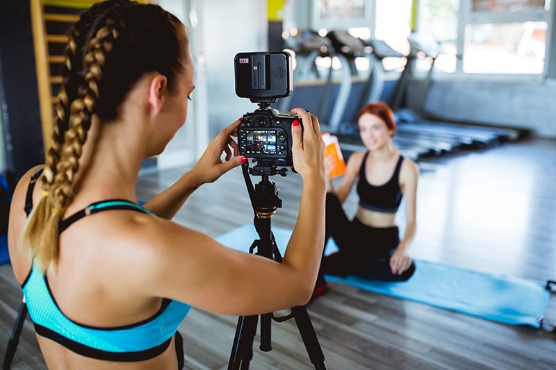 Fitness influencer being filmed by girl in active wear