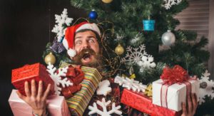 Bearded man wearing Santa hat and holding lots of gifts
