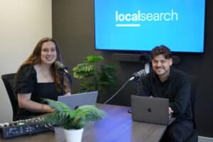 Daniel and Katrina Sitting at Table for Podcast Smiling at the Camera