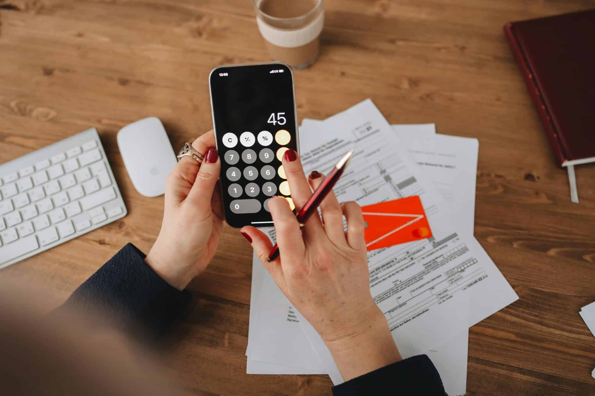 Lady using calculator on phone while paying bills